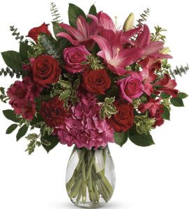 This luxe arrangement includes pink hydrangea, hot pink roses, red roses, dark pink asiatic lilies, dark pink alstroemeria, maroon carnations, pitta negra, spiral eucalyptus, and lemon leaf. Delivered in a glass jordan vase. Approximately 17" W x 18" H