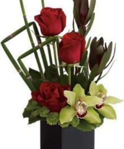 The imaginative bouquet includes red roses, leucadendron, green cymbidium orchids and green button spray chrysanthemums accented with fresh greenery.