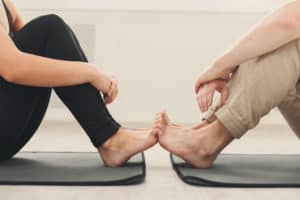 Two people on yoga mats touching feet